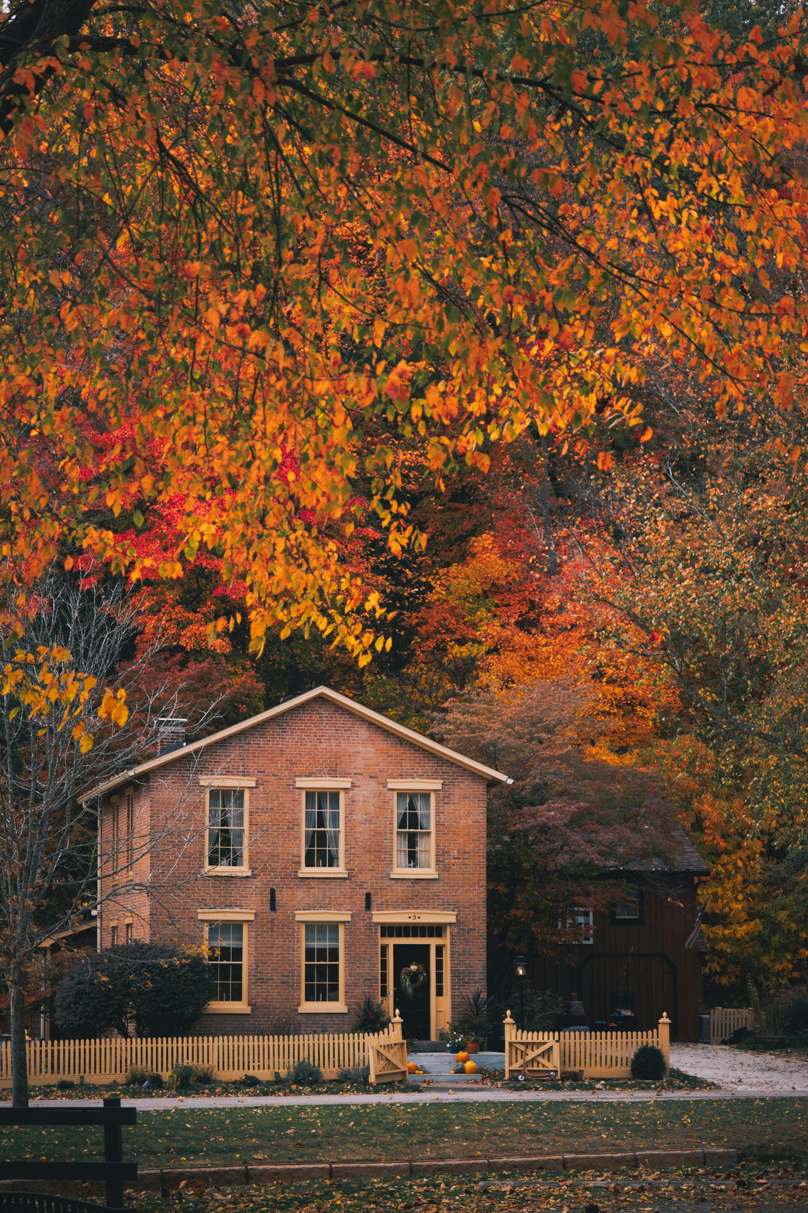 Brick home surrounded by orange and red fall foliage in autumn